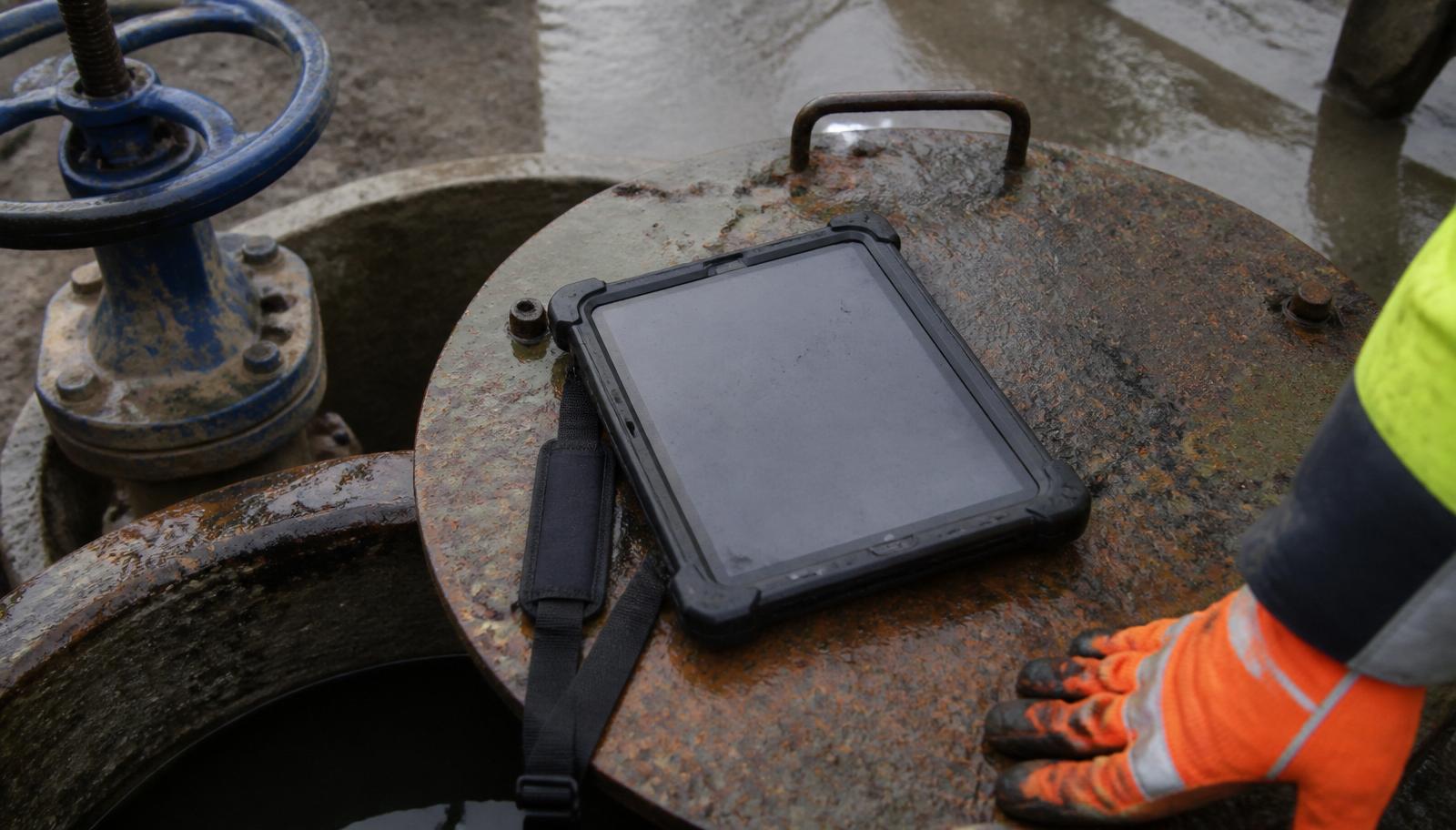 Kestrel R11 rugged tablet on a wet steel valve chamber lid at a water utility site
